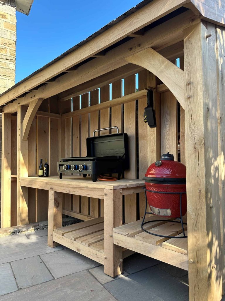 Woodson and Son oak pergola framing an outdoor seating and cooking area