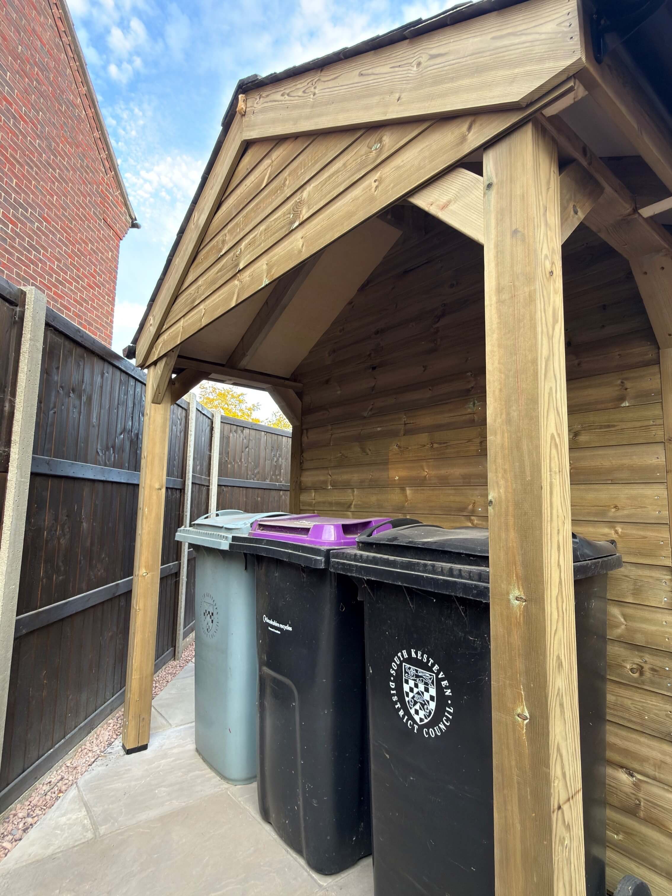 Covered wheelie bin storage area integrated into timber garden shed